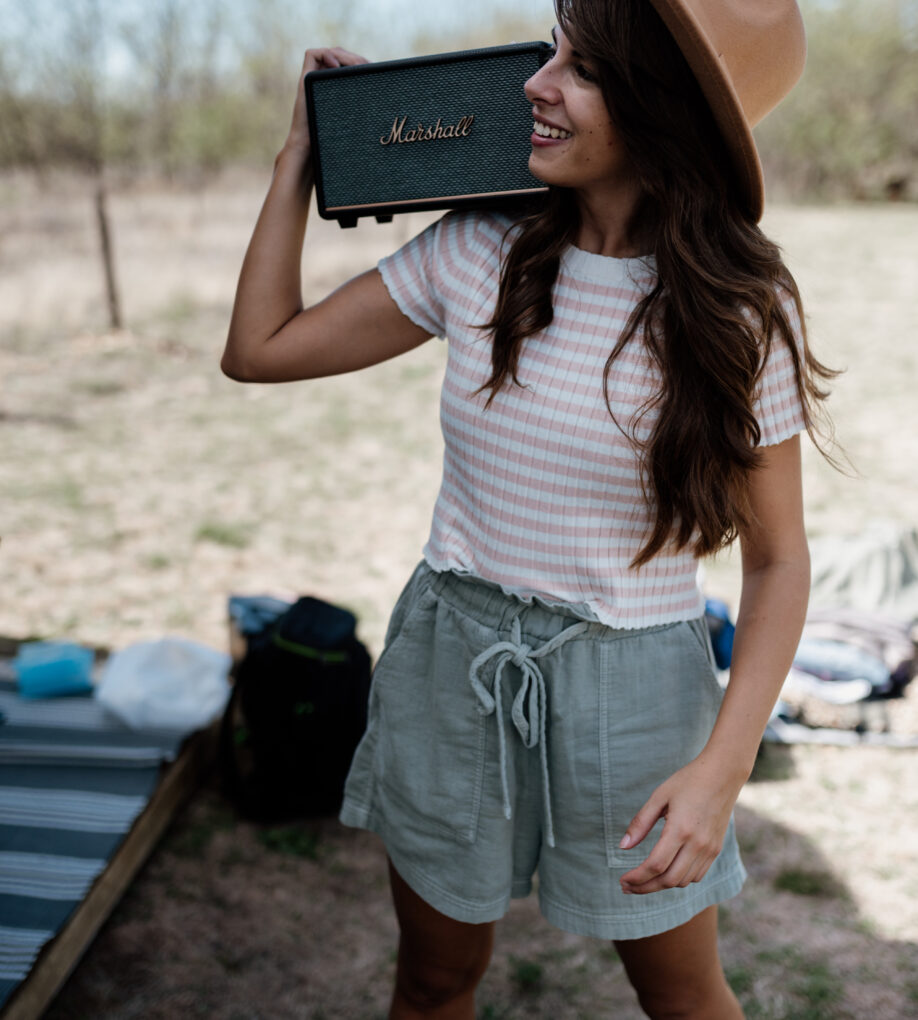 A young woman smiles as she holds a vintage portable speaker aloft
